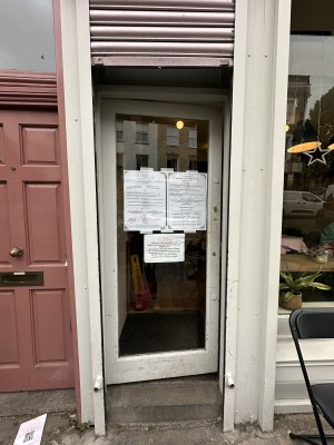 Glass door with white frame. Push from right to open.