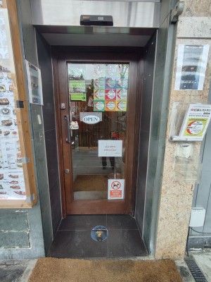 Brown framed glass door. Push black metal handle on left to open.