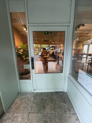 Green wooden and glass door ahead. Pull black metal handle on left to open.