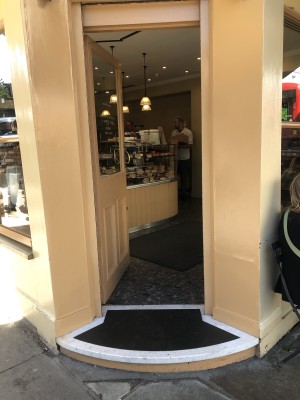 Glass door with yellow frame. Push handle on right to open.