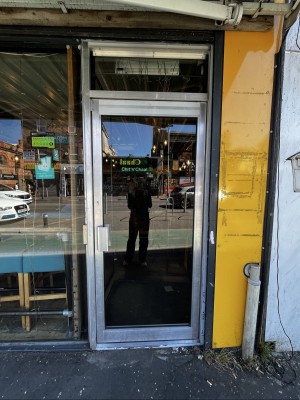 Glass door with metal frame ahead. Push from metal handle on left to open.