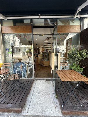 Ramp leading up to glass door. Pull wooden handle from left to open. Outdoor seating to left and right of it.