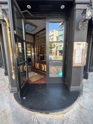 One step up to glass doors with black frames. Pull from centre to open.