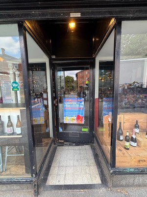 Glass door with black frames. Push from left to open.