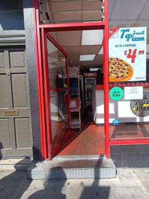 Glass door with red metal frame. Push from right to open.