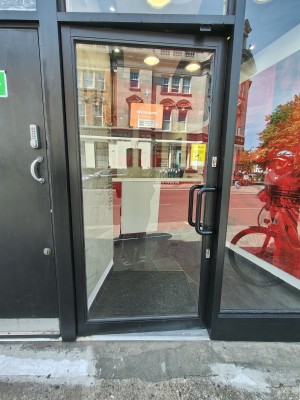 Black framed glass door. Push black handle on right to open.