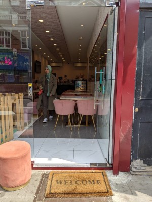 Glass door with metal handle on left. Push to open.