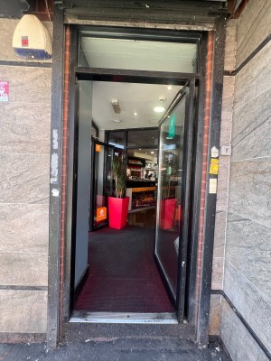 Black and glass panelled door ahead. Push from black metal handle on left to open.