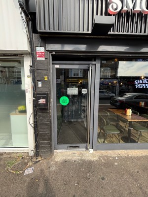 Glass door with metal frame. Push via grab rail on right to open.