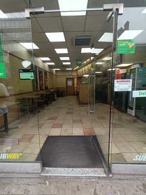 Glass door with silver metal handle on left. Push to open.