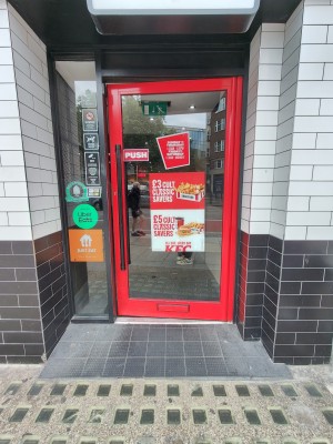 Red framed glass door. Push black handle on left to open.