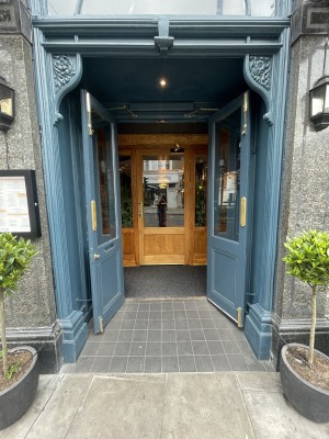 Blue glass and wooden doors ahead. Pull gold metal handles from centre to open.