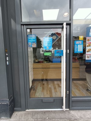 Glass door with grey metal frame. Push white handle from right to open.