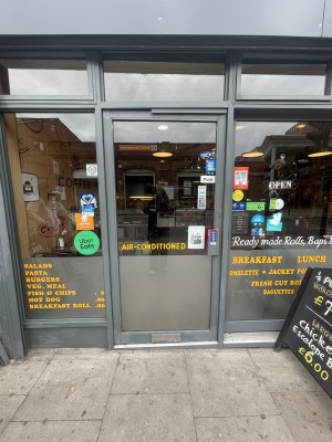 Glass door with grey frame aheaf. Push grey metal handle on right to open.