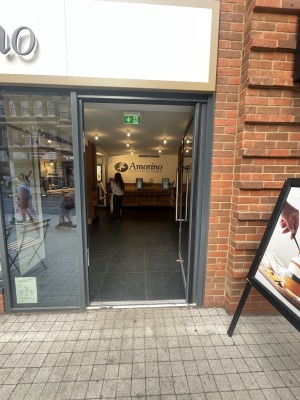 Glass door with grey frame ahead. Push silver metal handle on left to open.
