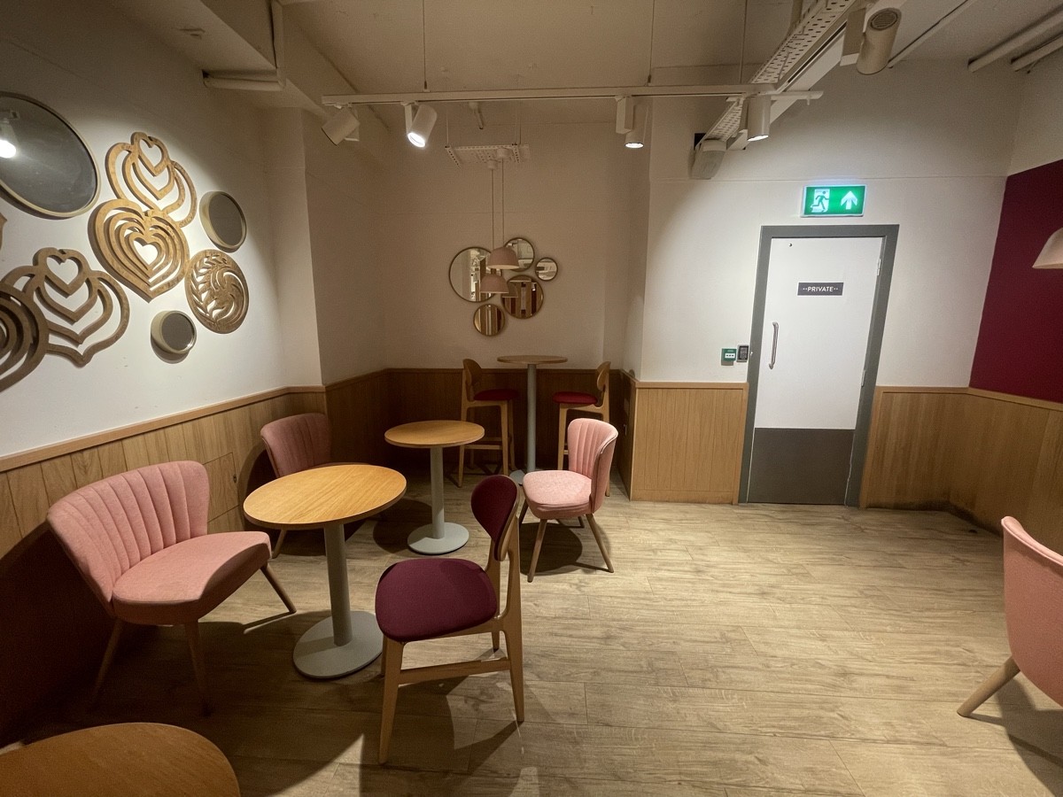 From glass divider facing straight. Armchairs, chairs and tables along left and to right.