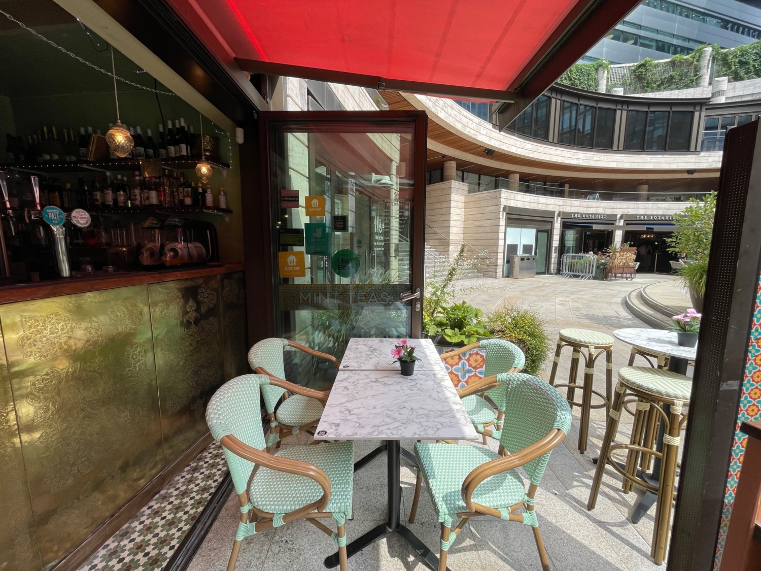 From outside entrance, facing right. Bar on left. Tables and chairs ahead. Reception desk on right. High tables at back right.