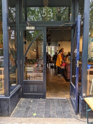 Glass doors with blue frame and metal handles in centre. Pull to open.