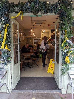 Glass doors with light green frame and metal handle in centre. Push to open.