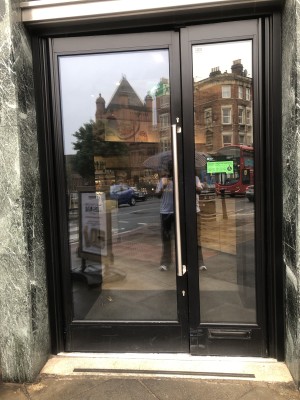 Glass doors with black frame. Push handle in centre to open.
