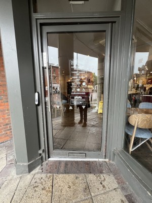 Grey and glass panelled door ahead. Push from metal handle on left to open.