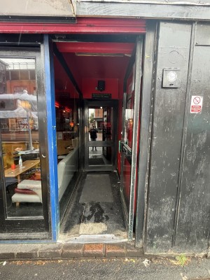 Single glass door with green handle. Push handle on left to open door.