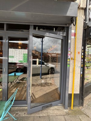 Glass door with grey frame. Pull via handle on left to open.