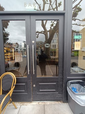 Glass door with black, wooden frame. Push from middle to open.