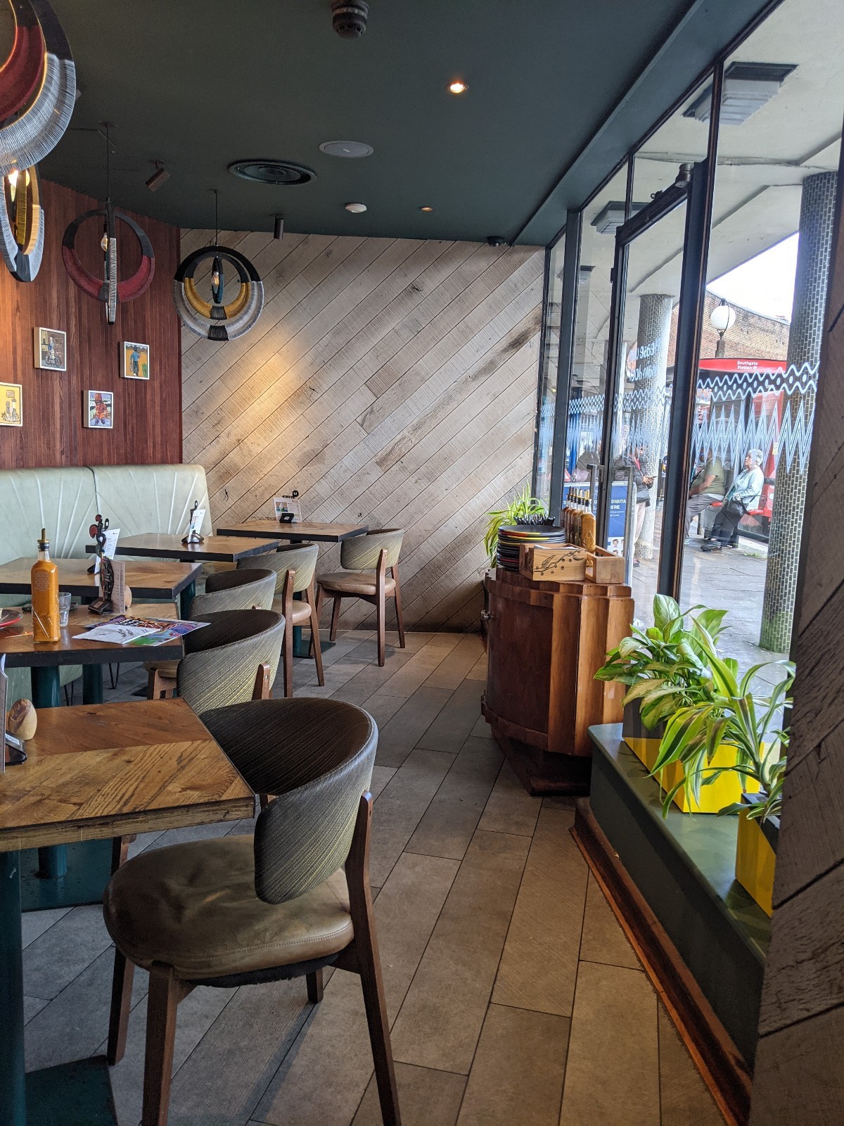 From door facing straight. Half booths with chairs along left. Plants on right, condiment station behind.