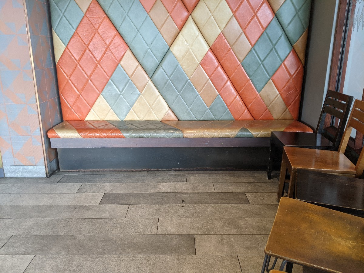 From after entrance facing right. Half booth at back. Chairs along right.