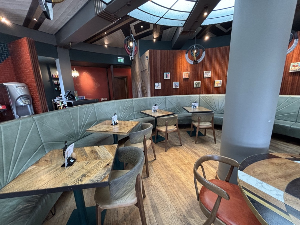 From divider facing left. Half booth along left and back. Table and column on right.