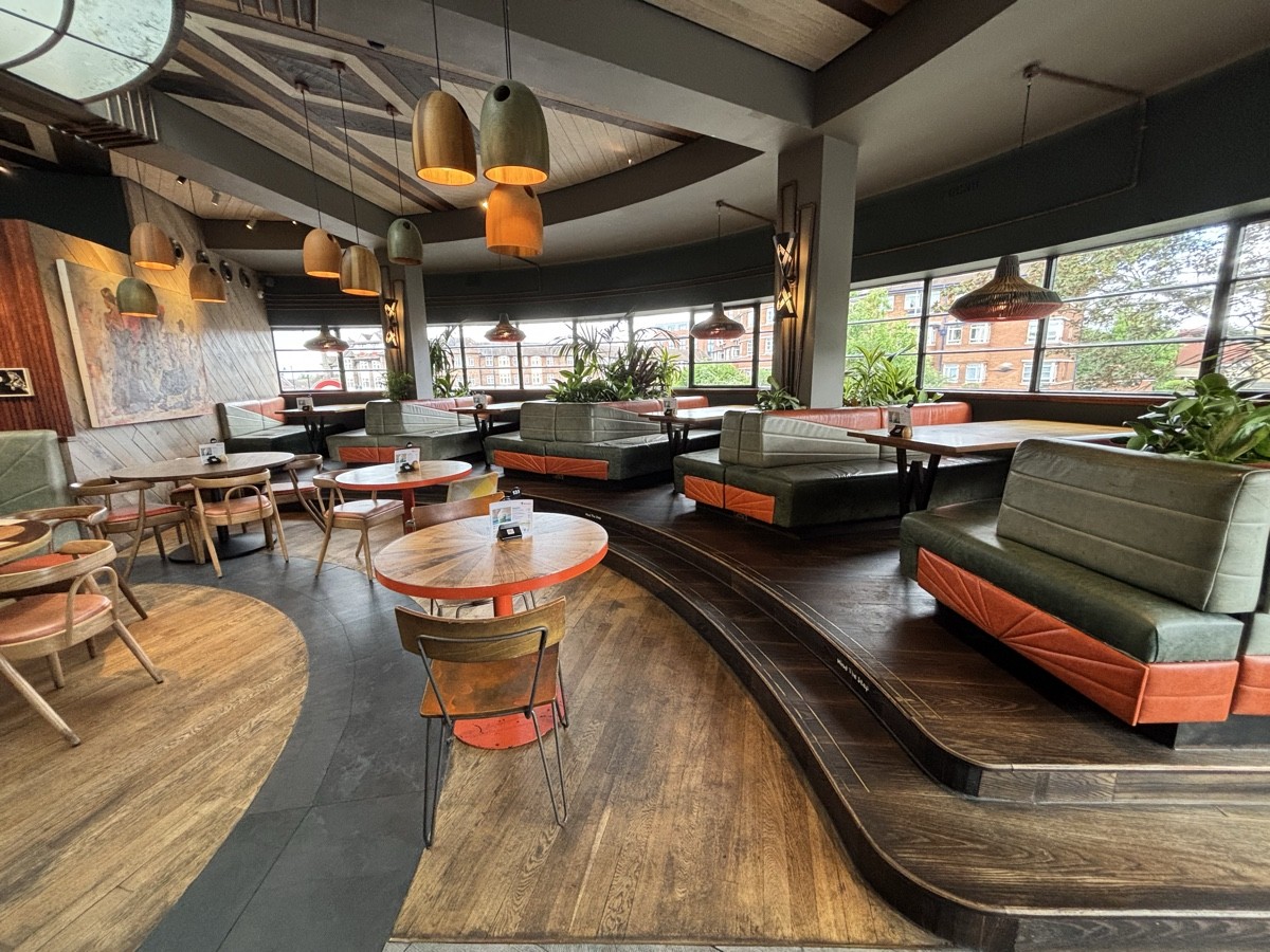 From end of divider facing straight. Tables and chairs ahead curving to left. Booths along right.