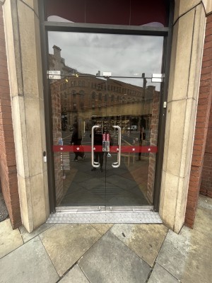 Glass doors with silver handles in centre. Pull from centre to open. Doorbell to left of doors.