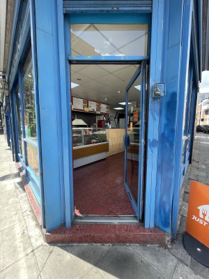 Glass door with blue frame ahead. Push blue metal handle from left to open.