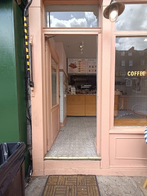 Glass door with peach wooden frame. Push from right to open.