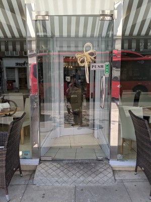 Glass door with metal handle on right. Push to open.
