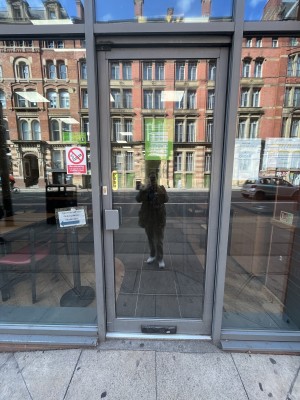 Grey framed glass door. Push grey handle on left to open.
