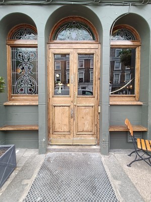 Glass door with brown, wooden frame ahead. Pull golden handle in middle to open.