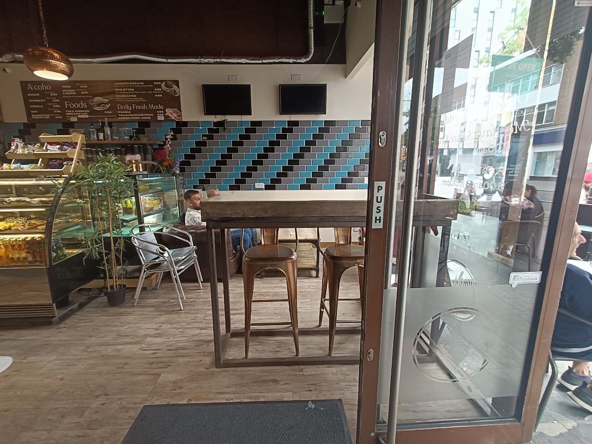From entrance, facing right. High tables and stools ahead. Tables and couches behind.