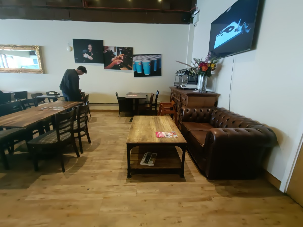 From table and chairs, facing left. Couche and table ahead on right. Tables and chairs at back and along left.