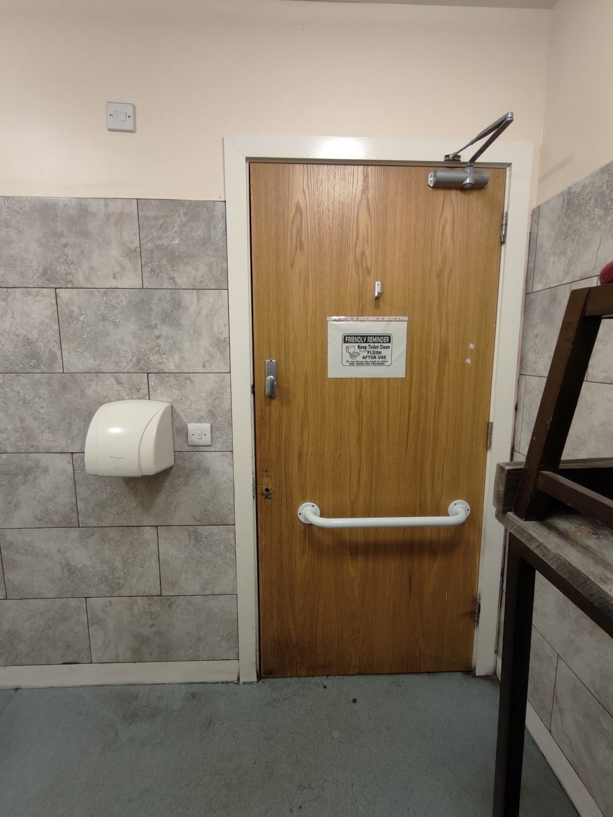 Back of door. White grabrail in centre. High hook above it. Pull from left to open.