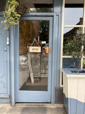Glass door with blue wooden frame ahead. Push from right to open.