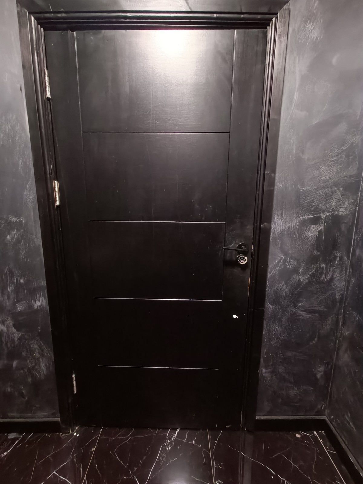 Back of bathroom door. Black metal handle and lock on right.