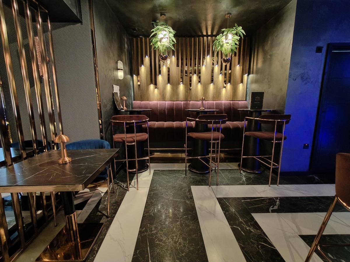 From beginning of bar facing left. Table and chairs on left. High half booth with stools at back.