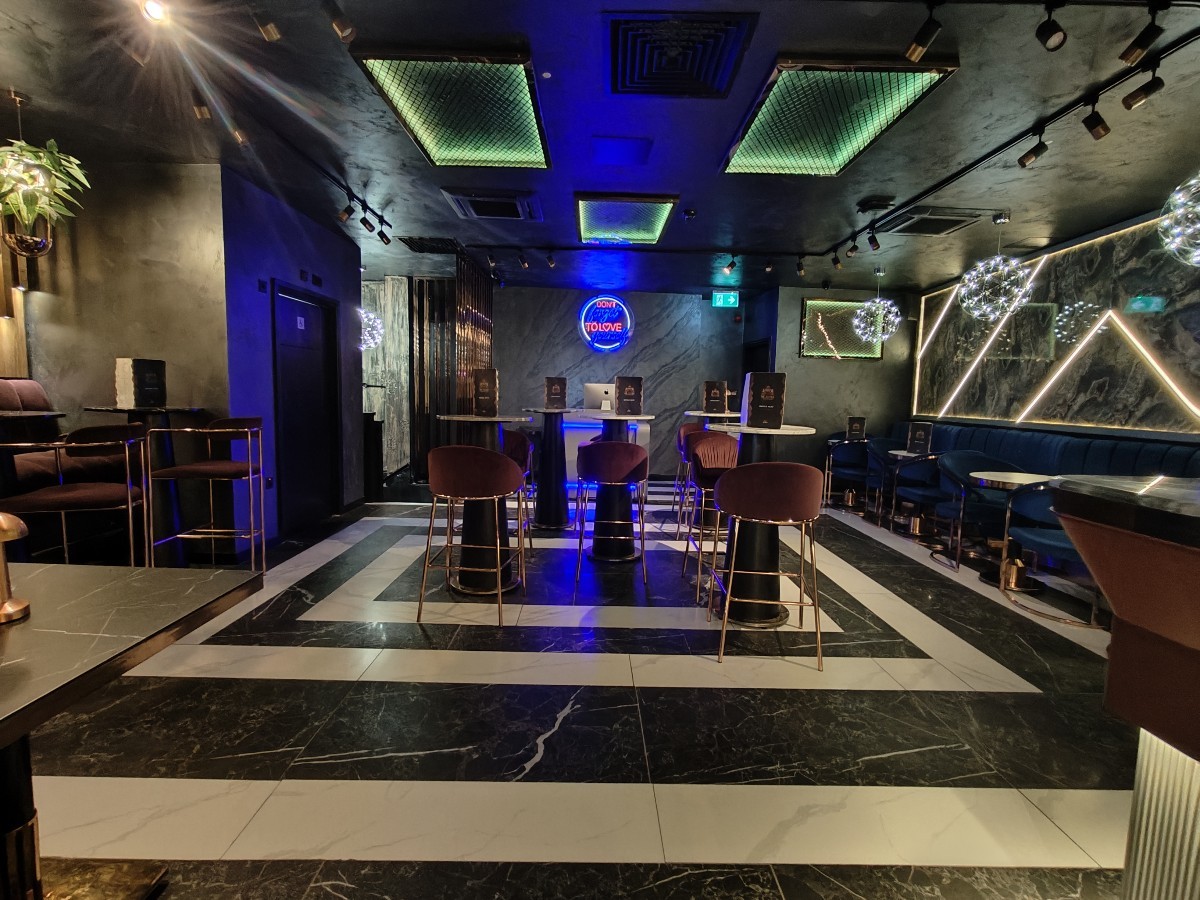 From beginning of bar facing left. Half booth on right. High tables and stools at back. Toilet to left of stools.