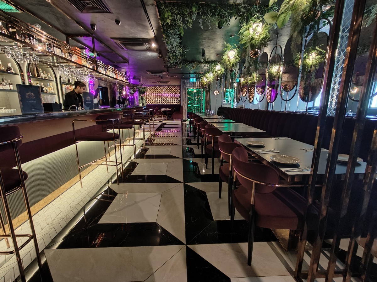 From after second metal partition facing right. Half booth along right. Path in centre to more seating. Bar and stools on left.