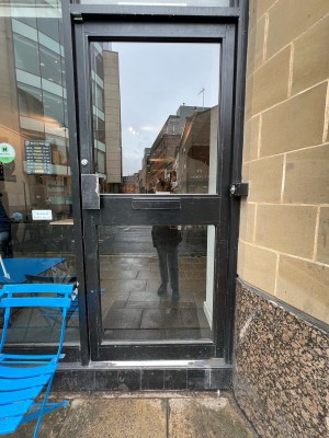 Black and glass door ahead. Push from metal handle on left to open.