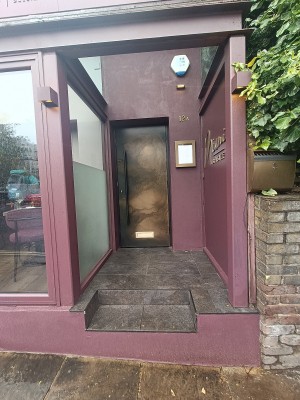 From street, facing venue. Two steps ahead. Doorway at back.