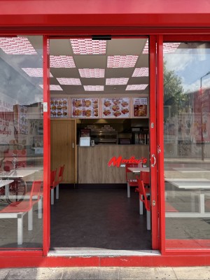 Glass door with red doorframe. Handle on left. Slide right to open.