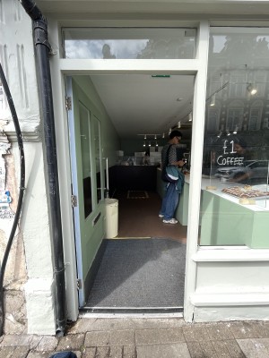 Facing green door with glass panels. Push sliver handle on right to open.